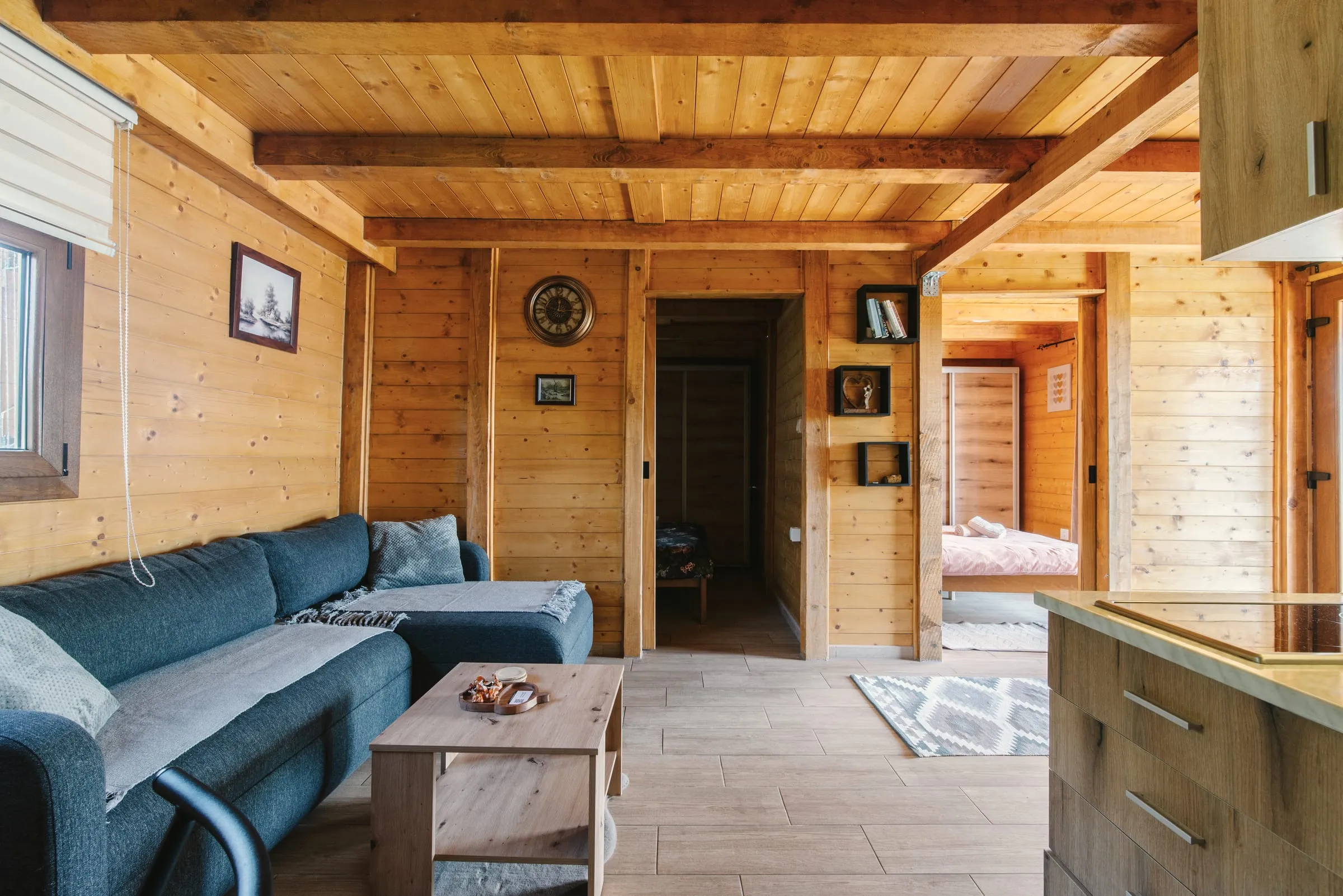 Ruang keluarga kabin berdinding pinus dengan sofa biru